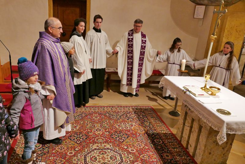 Bischof, Kinder und Ministranten stehen um den Altar