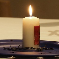 Kerze auf einem Teller, daneben ein Stück Stacheldraht vom Eisernen Vorhang  