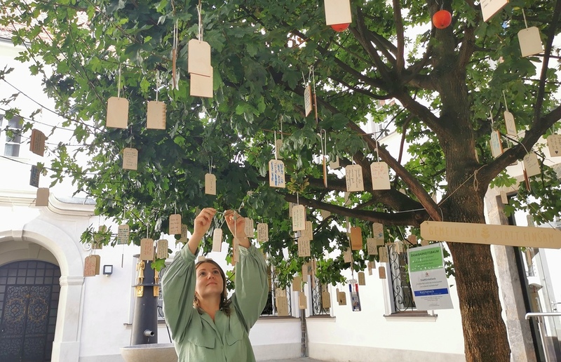 Sozialarbeiterin Emanuela Ratiu hängt eines von fast 300 DANKE-Worten auf den Dankbarkeitsbaum im Brunnenhof. Aus den beschrifteten Holzplättchen ist eine „DANKE-Skulptur“ entstanden, die im Kircheneck ausgestellt wird.